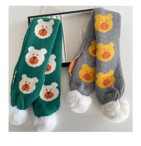 Détail d'écharpes tricotées pour enfants en gris et vert avec ours et pompons blancs