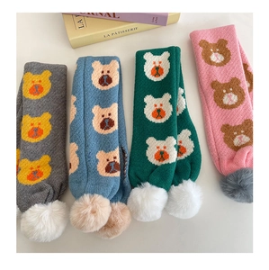 Détail de quatre écharpes tricotées pour enfants avec motifs d'ours et pompons en peluche