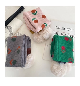 Dettaglio di sciarpe in maglia per bambini con motivi floreali e morbidi pompon