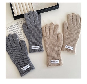 Detailed close-up of knitted children's gloves in grey and khaki with a quality logo tag