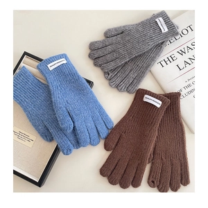 Detailed macro view of knitted winter gloves showing ribbed texture and woven quality label