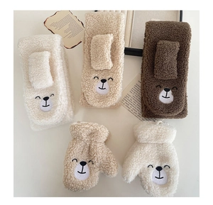 Detailed close-up of fluffy lamb wool winter scarf and gloves with bear embroidery