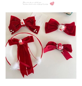 Close-up of red velvet bow hair clips with plush pom-poms and festive Chinese charms