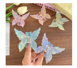 Détail de cinq pinces à cheveux papillon nacrées irisées sur une surface en bois chaud