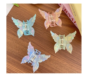 Détail de quatre pinces à cheveux papillon en acétate irisé sur un bureau en bois