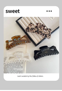 Detailed macro view of four acetate hair claws in leopard, amber, pearl white, and black