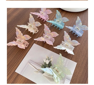 Vue à plat de pinces à cheveux papillon colorées aux tons pastels sur une table en bois