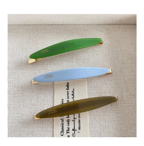 Detail view of willow leaf acetate hair clips in green and blue with gold spring base
