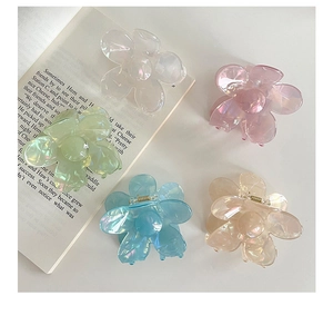 Gros plan de cinq pinces à cheveux fleur en acrylique avec fini iridescent sur livre