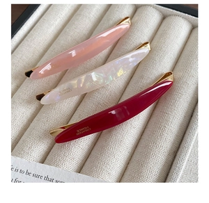 Detailed close-up of acetate hair clips in pink and red with Creation France gold stamps