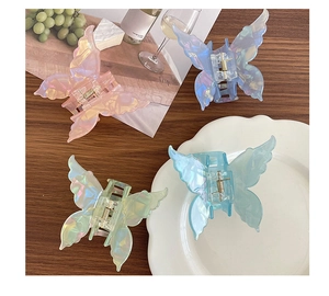 Détail de 4 pinces à cheveux papillon irisées posées sur un plateau décoratif élégant