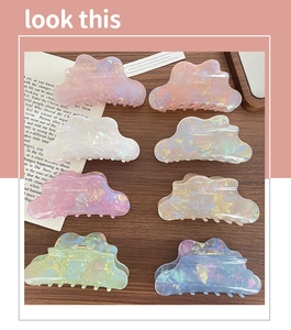 Iridescent wavy cloud hair claws in pastel colors displayed on a rustic wood surface