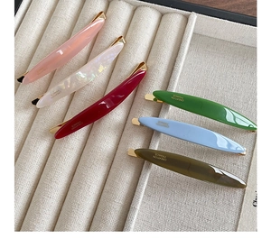 Detailed macro view of acetate hair clips in various colors with golden metal base