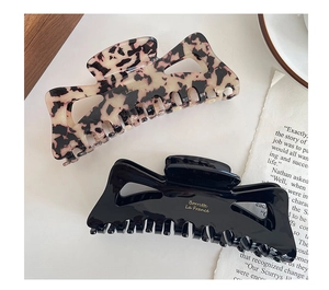 Detail view of large French acetate claw clips in tortoiseshell pink and solid black