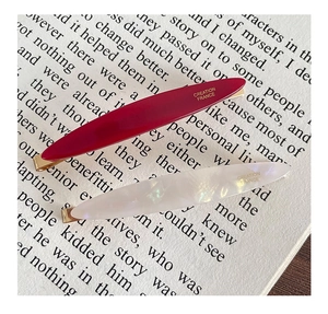 Macro detail of French acetate hair clips in pearl white and deep red with gold logo