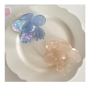 Détail de pinces à cheveux fleurs en acrylique bleu et rose avec effet perlé sur plateau