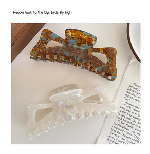 Detailed macro view of large acetate hair claws in tortoiseshell blue and pearl white finish