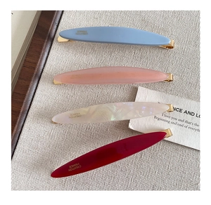 Detailed view of four acetate hair clips in candy colors with golden metal base