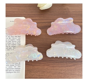 Detail of four colorful iridescent acetate hair claws in pink and white on wood