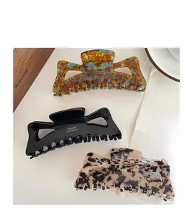 Detail of three acetate hair claws in amber, black, and leopard print with metal logo