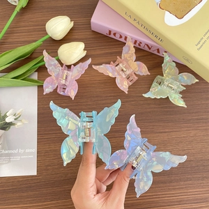 Pinces à cheveux papillon irisées en plusieurs couleurs sur fond de table en bois