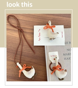 Close-up of cute fabric goose hair clip and necklace set with bow details