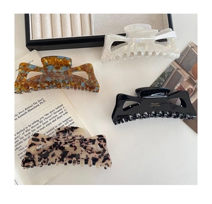 Detail of four acetate claw clips in marble and leopard patterns with gold lettering