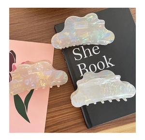 Iridescent mermaid-style hair claw clips in cloud shape set on wooden table detail