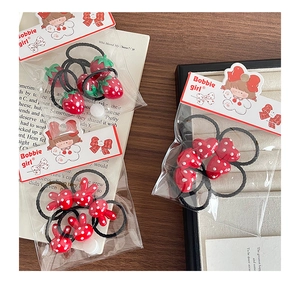 Detailed view of red polka dot hair ties with strawberry, heart, and rabbit charms