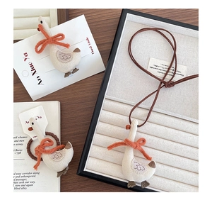 Detailed view of handmade embroidered goose hair clips and necklace set with orange bows