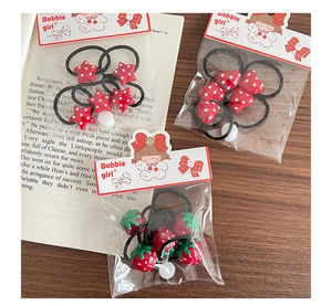 Detailed view of red polka dot star and heart shaped hair ties for little girls
