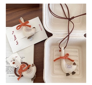Detailed view of handmade fabric duck hair clip and necklace set in a cozy aesthetic