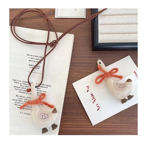 Detail of cute fabric goose pendant with knitted orange bow and delicate stitching