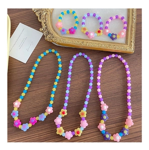 Collane e bracciali di perle di fiori acrilici colorati su una cornice dorata vintage