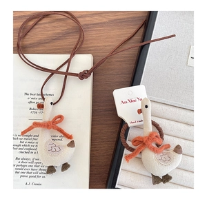 Detailed view of handmade fabric goose necklace and hair ring with orange bow accents