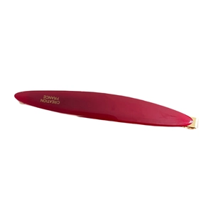 Minimalist deep red acetate hair clip with gold logo detail on a clean white background