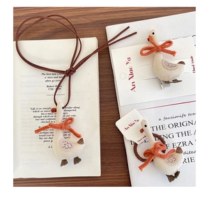 Detail of handmade fabric goose hair clip and necklace set with cute orange bow accents