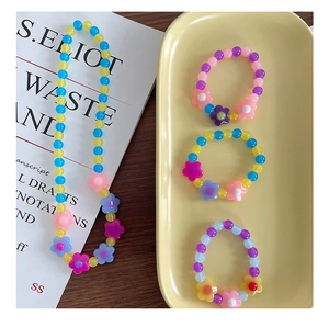 Dettaglio di collana e bracciale con fiori di acrilico colorati per bambine