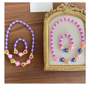 Dettaglio del set collana e bracciale con perline a fiore su una cornice vintage