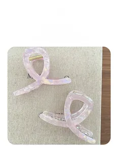 Dettaglio di fermagli per capelli in acetato rosa perlato con design a nastro incrociato