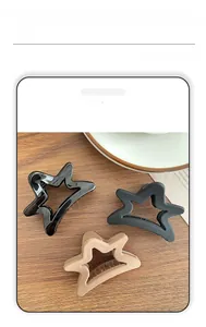 Three star-shaped claw clips in matte grey, black and tan on a wooden background