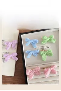 Detailed view of colorful knitted bow hair clips with metallic duckbill attachment
