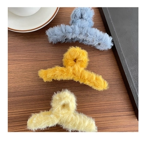 Vue détaillée de grandes pinces à cheveux en peluche gris-bleu, gingembre et beige sur bois