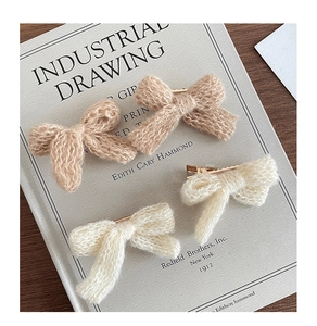 Detail view of four knitted bow hair clips in beige and brown with metal duckbill clips