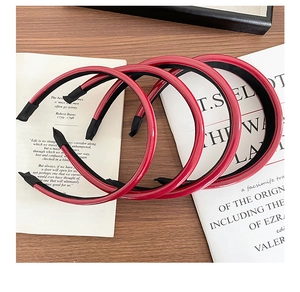 Detailed view of three glossy red PU leather headbands on vintage books for women