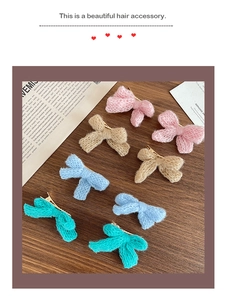 Detailed view of eight knitted bow hair clips in assorted colors on a vintage wooden surface