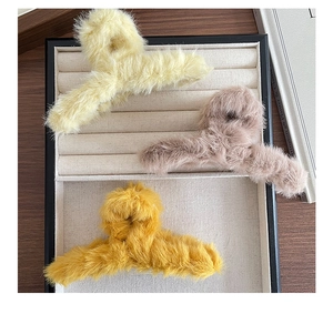 Gros plan sur des pinces à cheveux en peluche douce en jaune, rose et moutarde sur velours