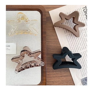 Detailed set of four star-shaped matte hair claws in various earthy tones on vintage tray