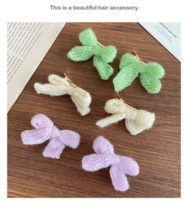 Close-up of six handmade knit bow hair clips in pastel colors on wooden surface