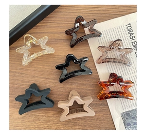 Detail of star-shaped hair claws in matte and glossy finishes on wooden background